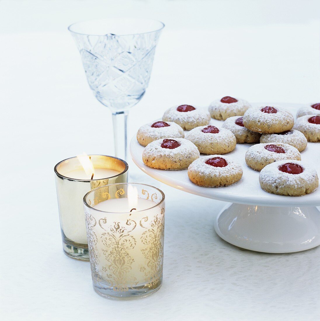 Jam biscuits on a cake stand with candle glasses