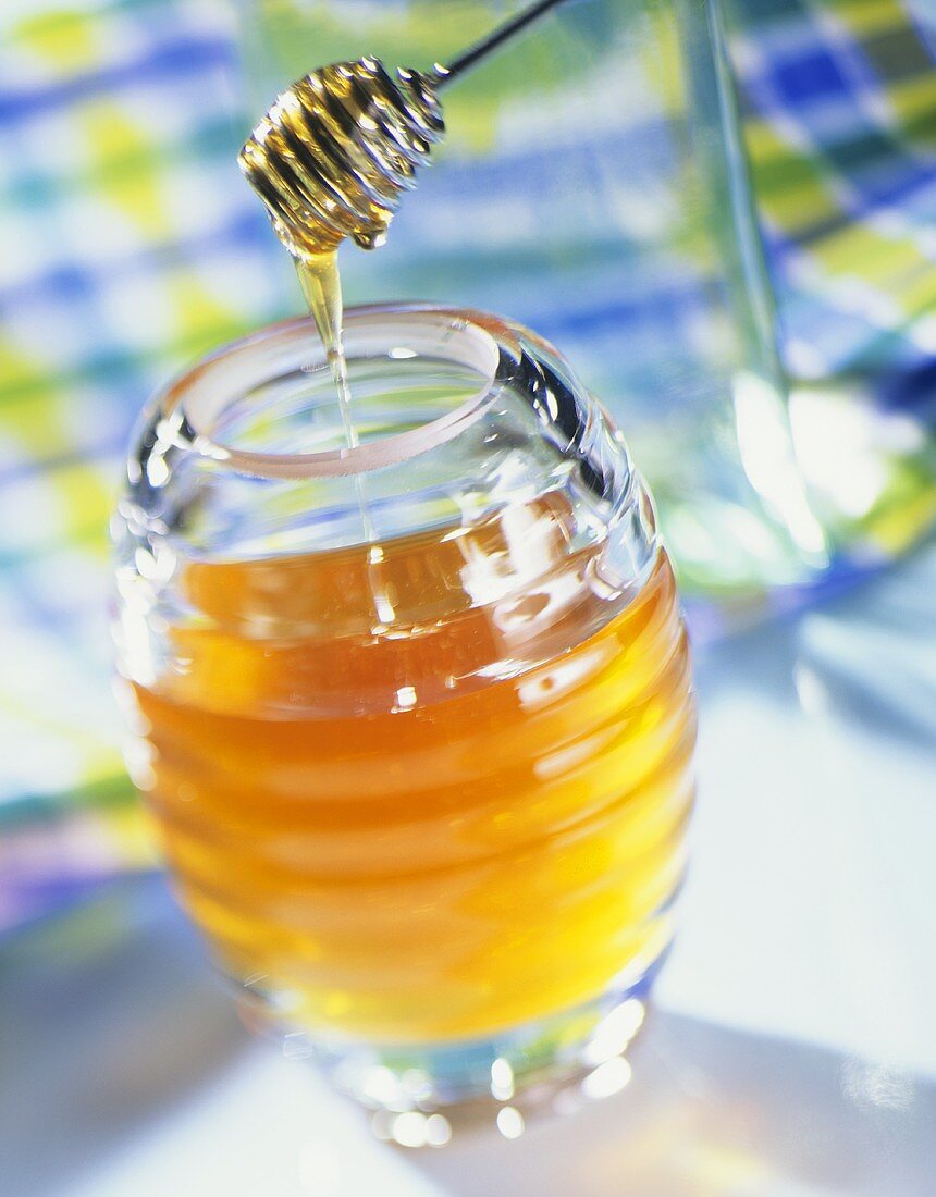 A jar of honey with a honey dipper