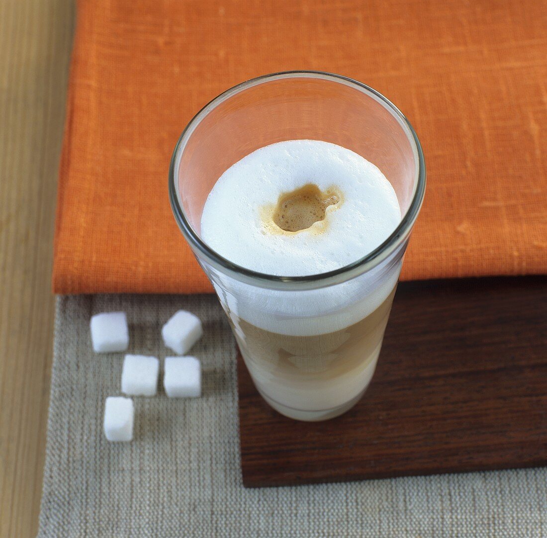 Glass of latte macchiato with sugar cubes