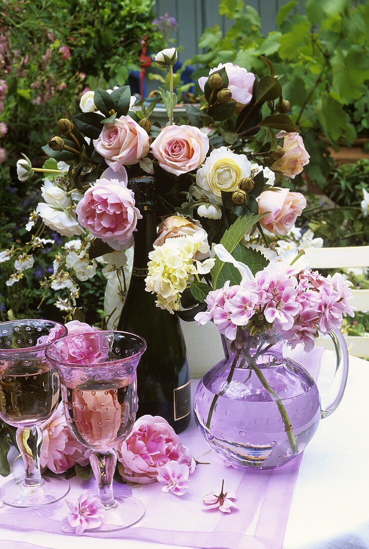 Weißwein mit Sommerblumenstraus auf einem Gartentisch
