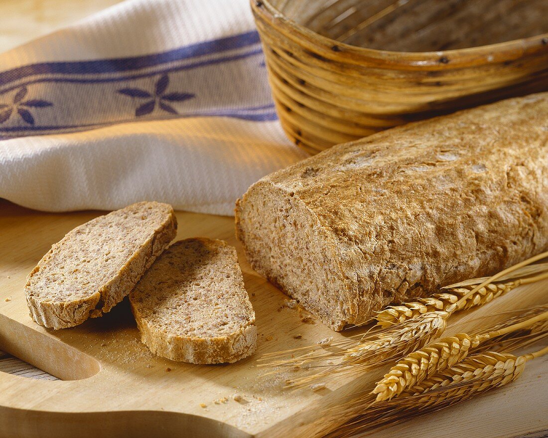 Sourdough rye bread, partly sliced on wooden board