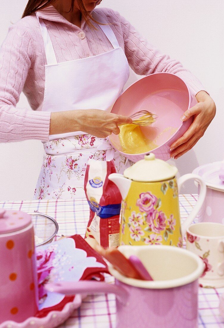 Junge Frau beim Backen verquirlt Eier