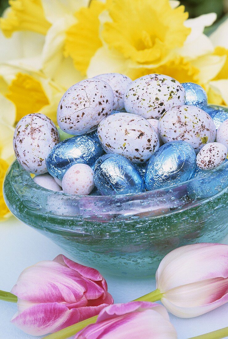 Easter eggs in blue glass bowl, spring flowers