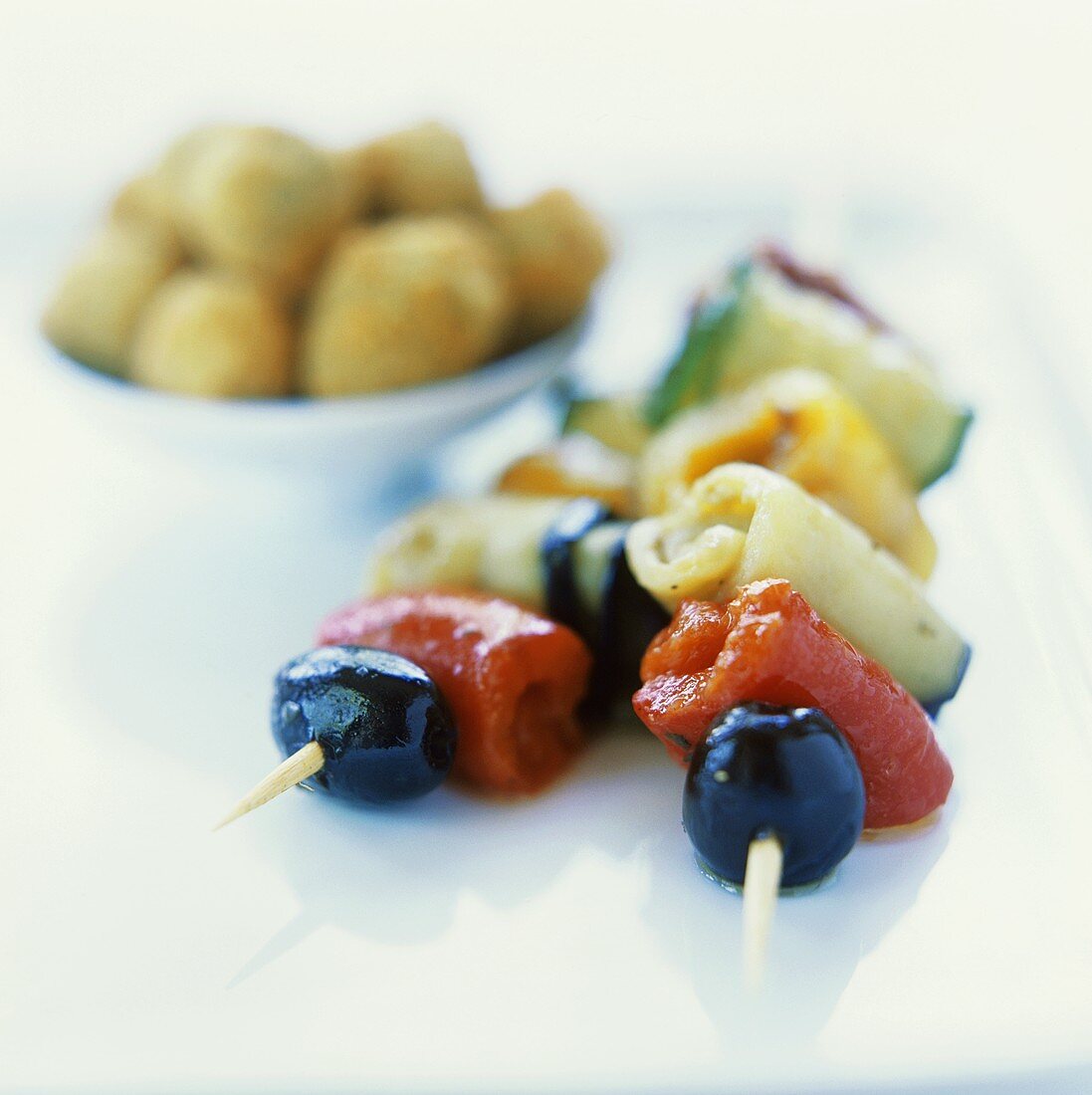 Grilled vegetable skewers and deep-fried olives
