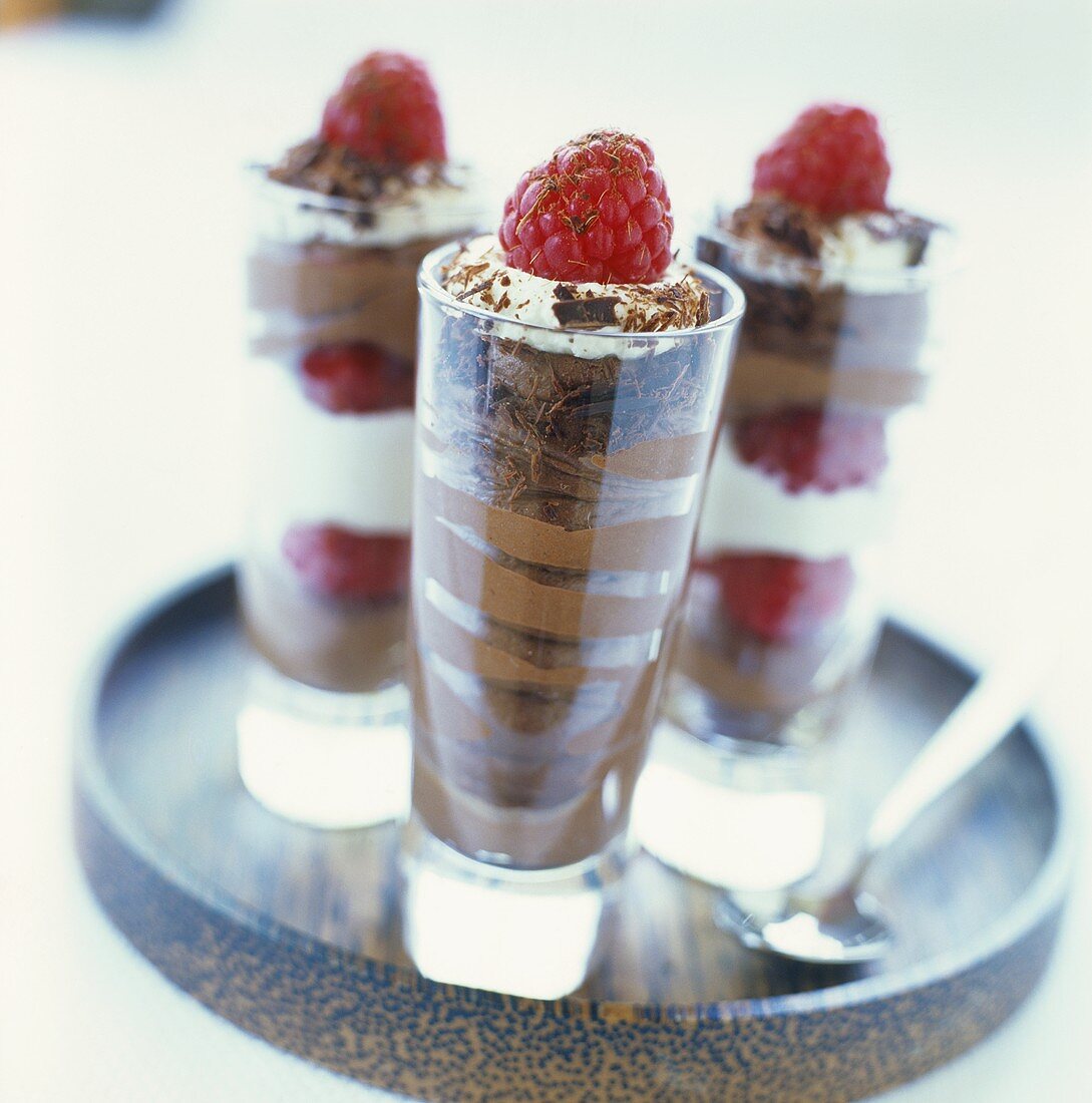 Chocolate mousse with raspberries and whipped cream in three glasses