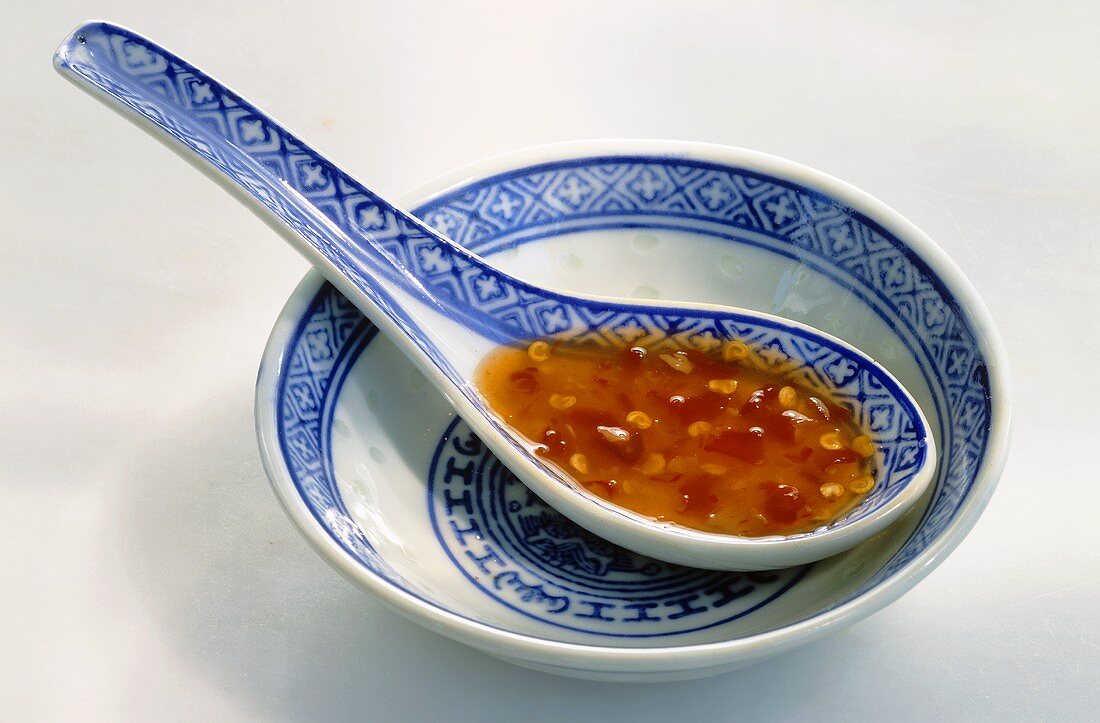 Sweet chilli sauce in porcelain spoon in small dish