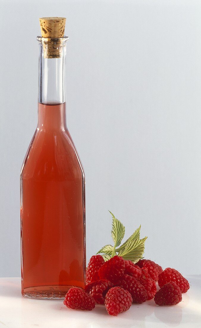 Flasche Himbeeressig mit frischen Himbeeren