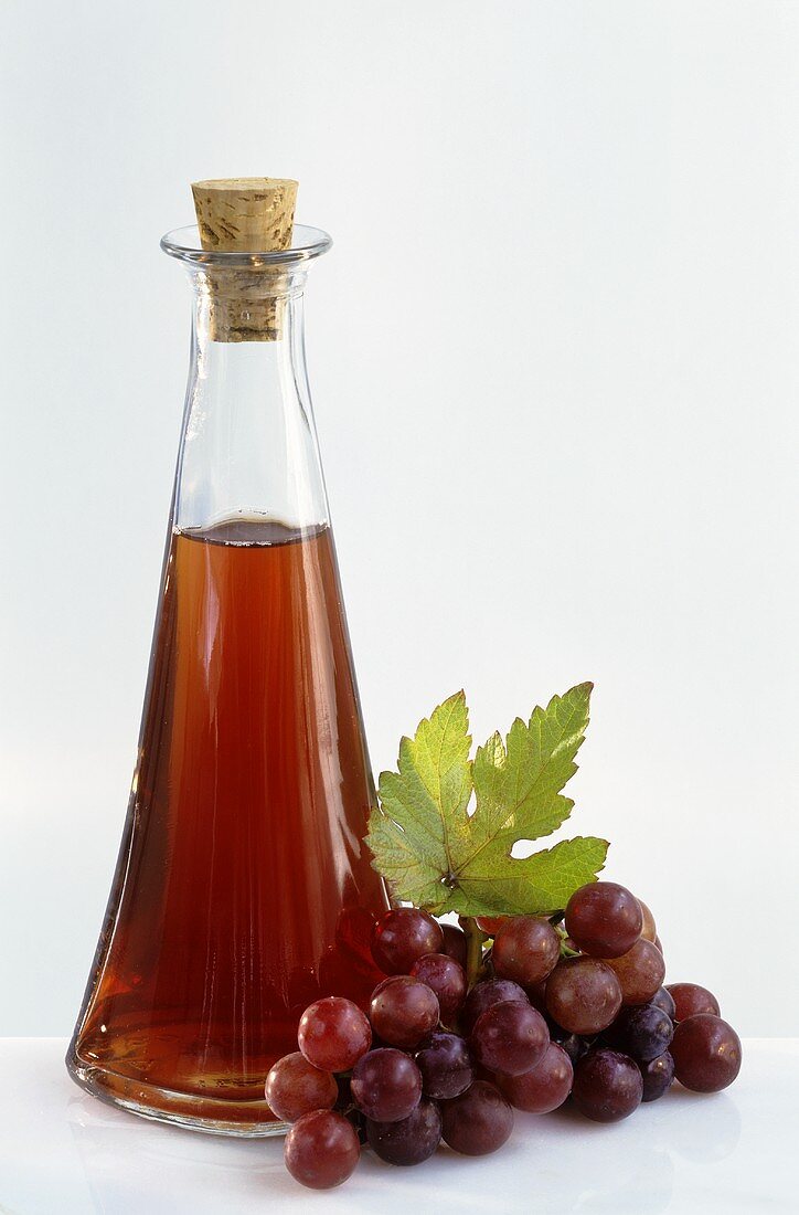 Eine Flaschen Traubenessig mit frischen Trauben