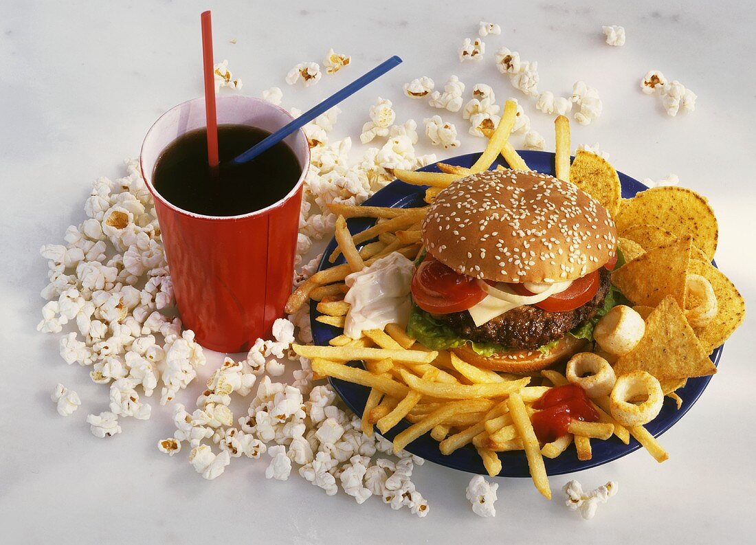 Ungesunde Ernährung: Burger, Pommes, Popcorn, Cola, Chips