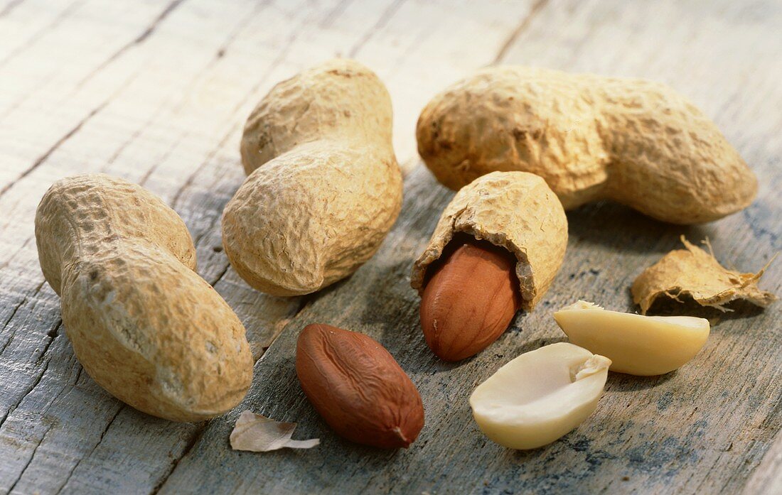 Shelled and unshelled peanuts on wooden background