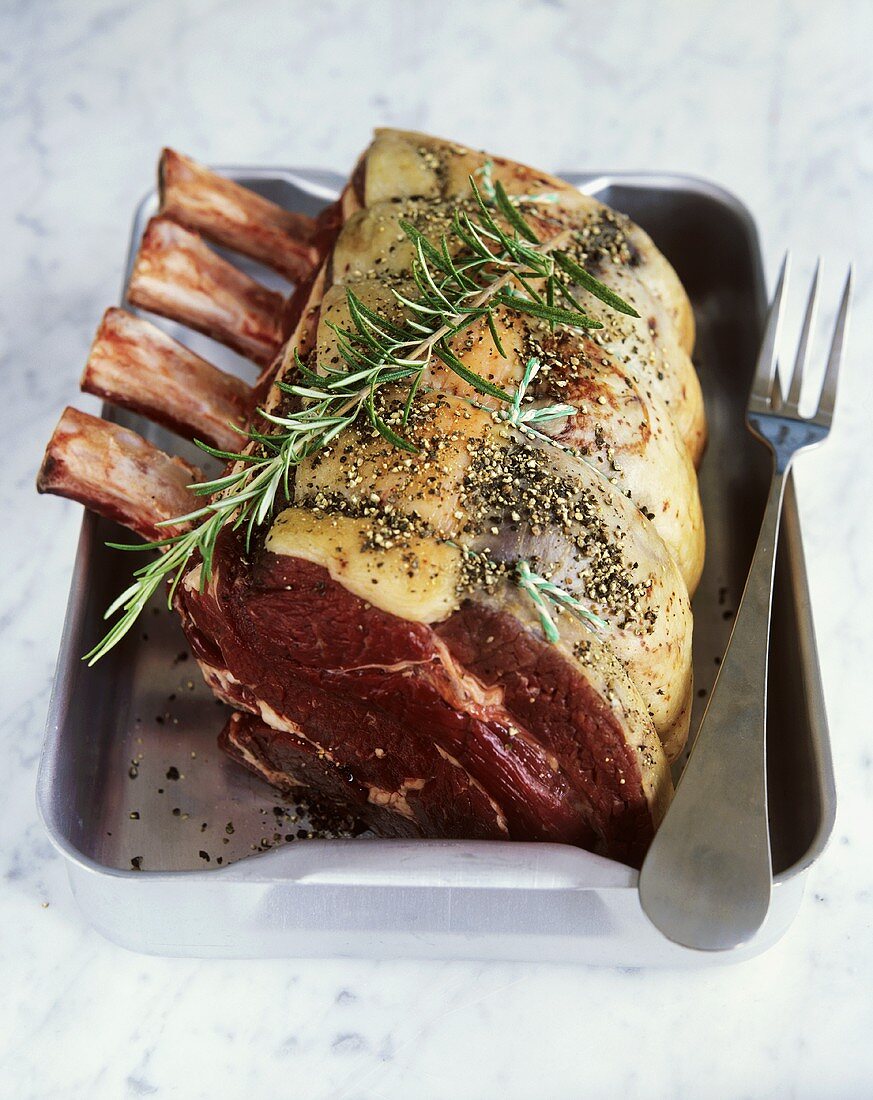 Rib of beef with rosemary and pepper in a roasting tin