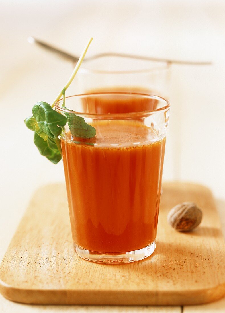 Two glasses of tomato juice with nutmeg and basil
