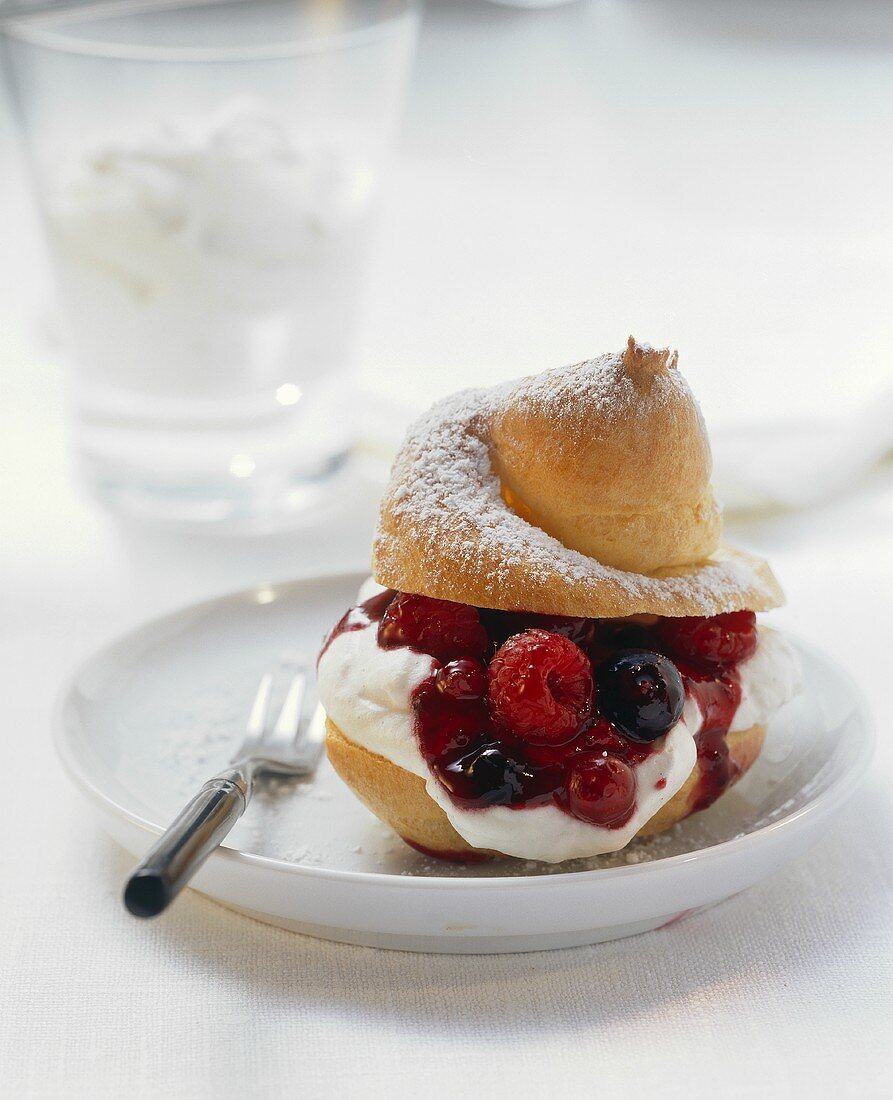 Profiterole filled with whipped cream and red berry compote