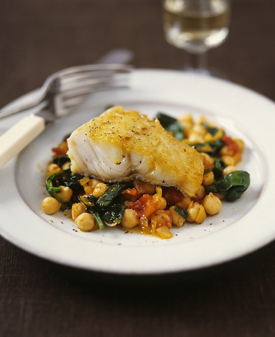 Fried hake on a bed of chickpeas and vegetables