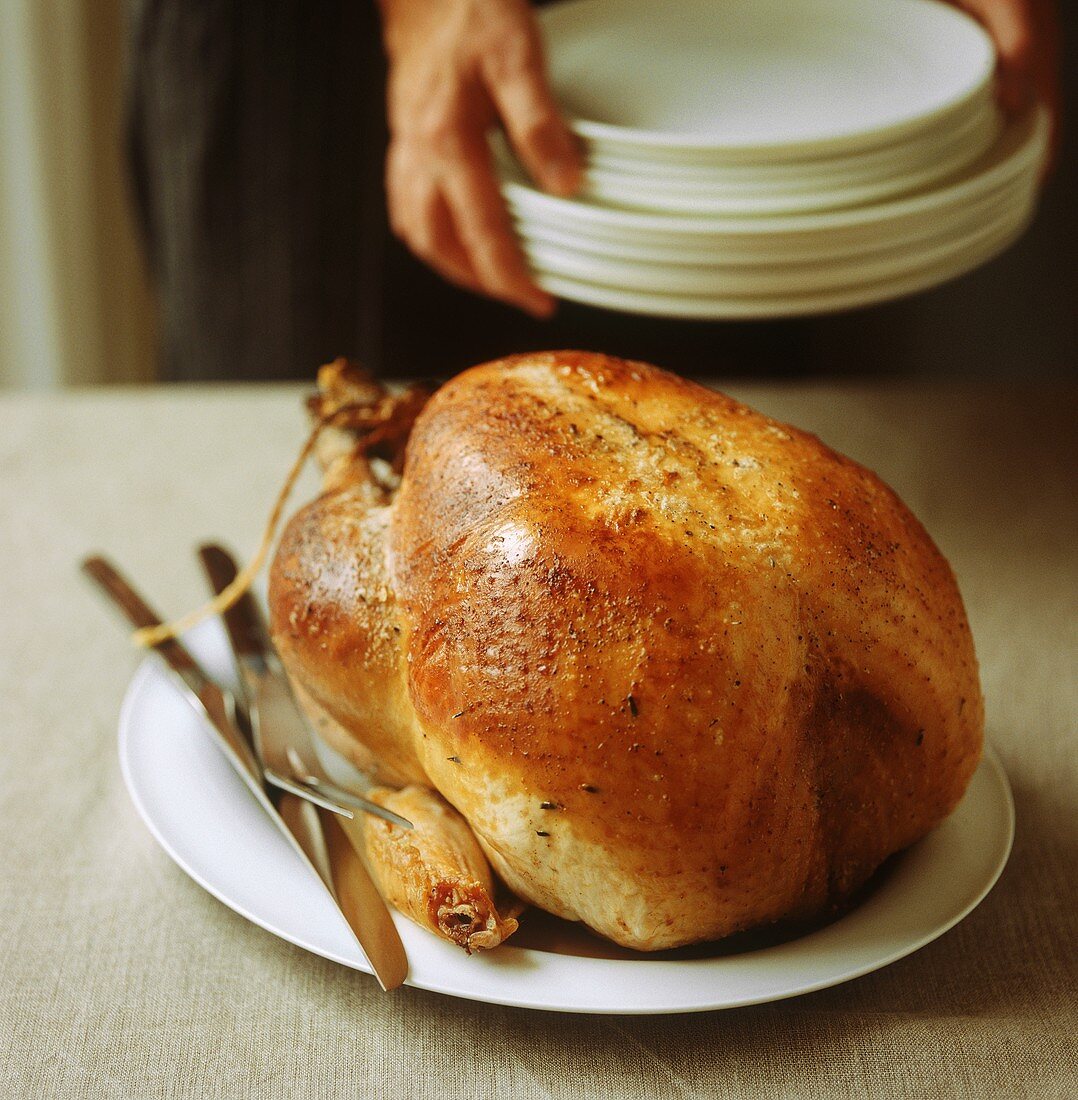 A whole roast turkey with carving knife and fork