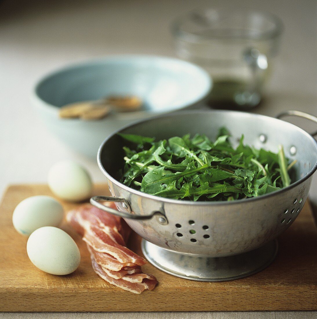 Dandelion leaves in a colander with bacon and eggs