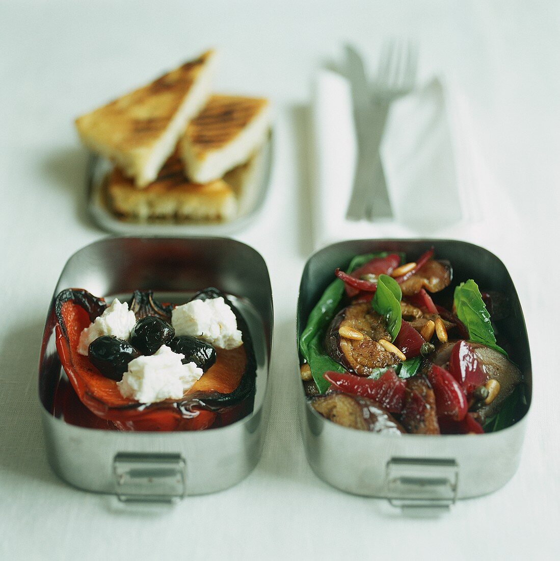 Two lunch boxes with grilled vegetables and feta