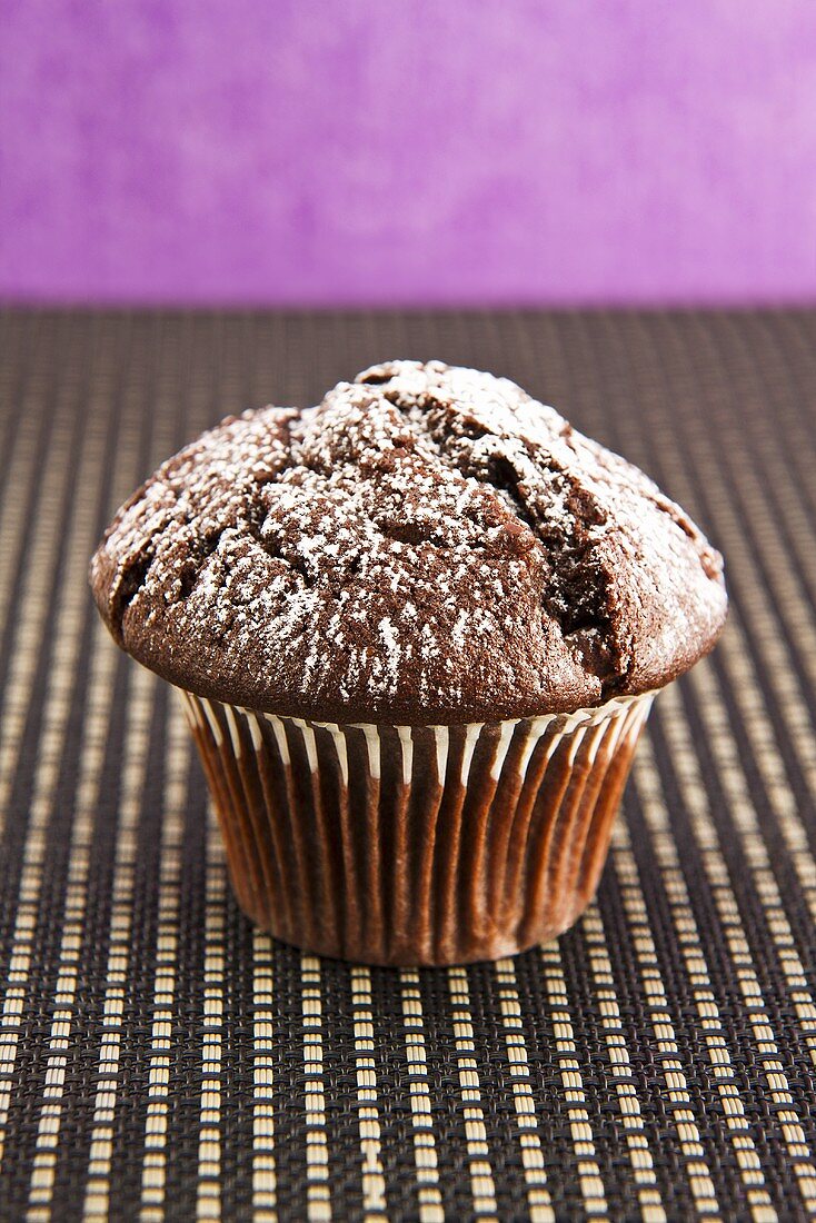 A chocolate muffin with icing sugar