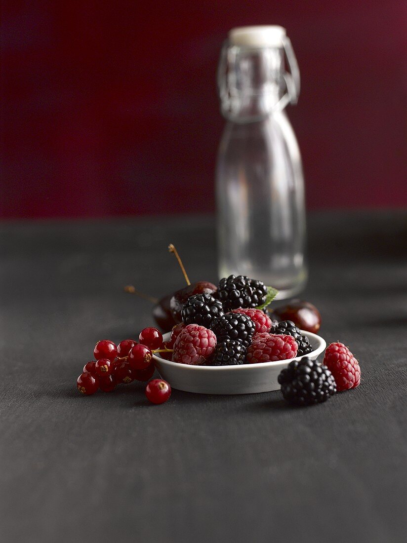 Fresh berries and a glass bottle in the background