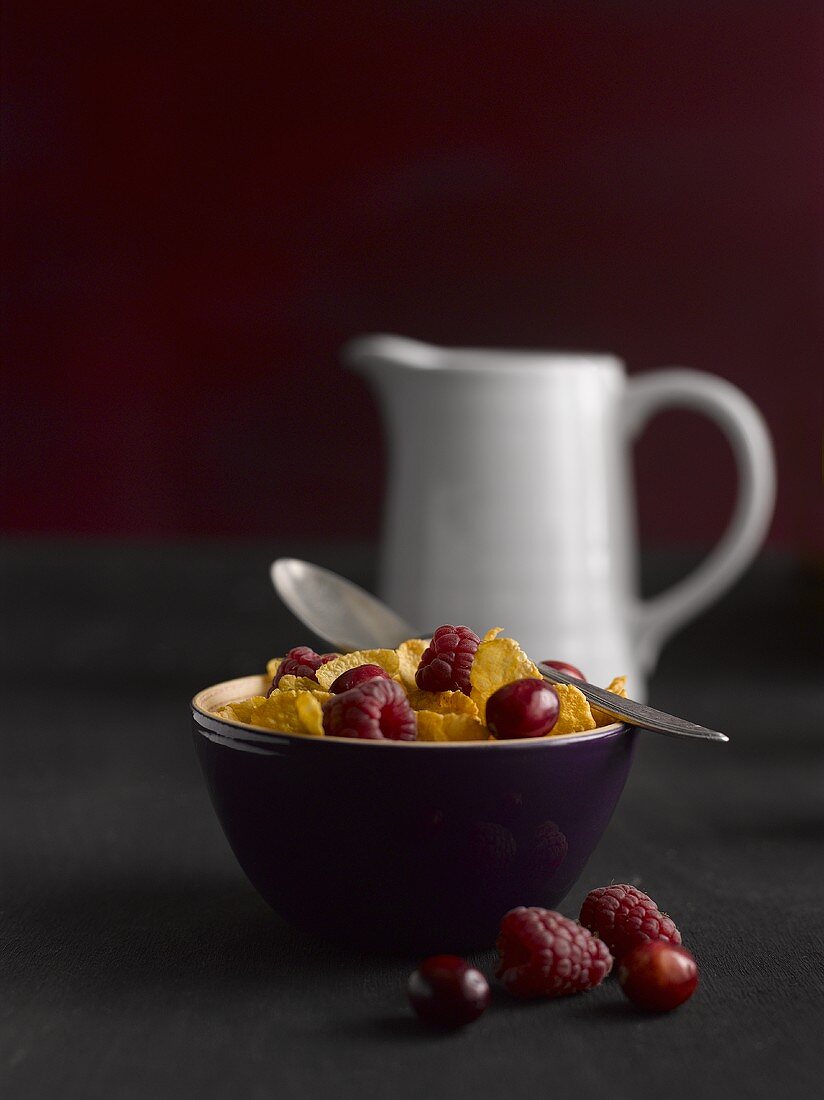 Cornflakes with berries and a milk jug