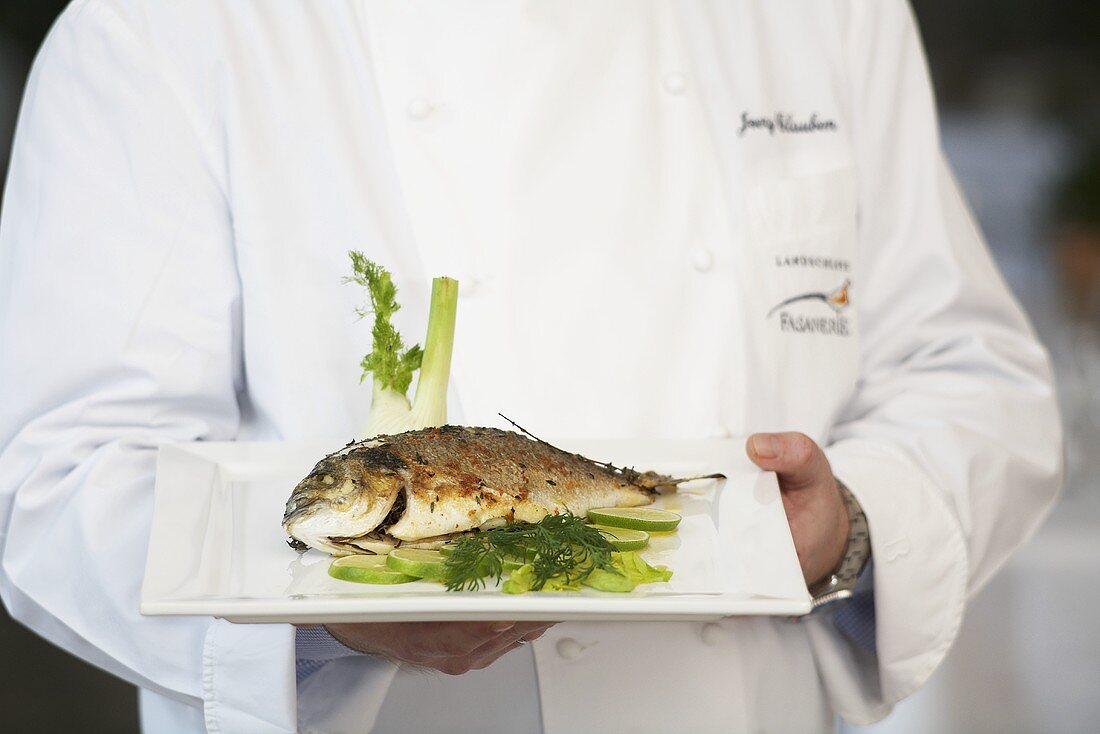 Koch serviert Fisch mit Fenchel und Limetten