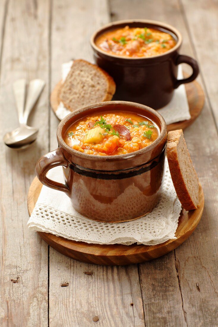 Two cups of hot lentil soup with bread