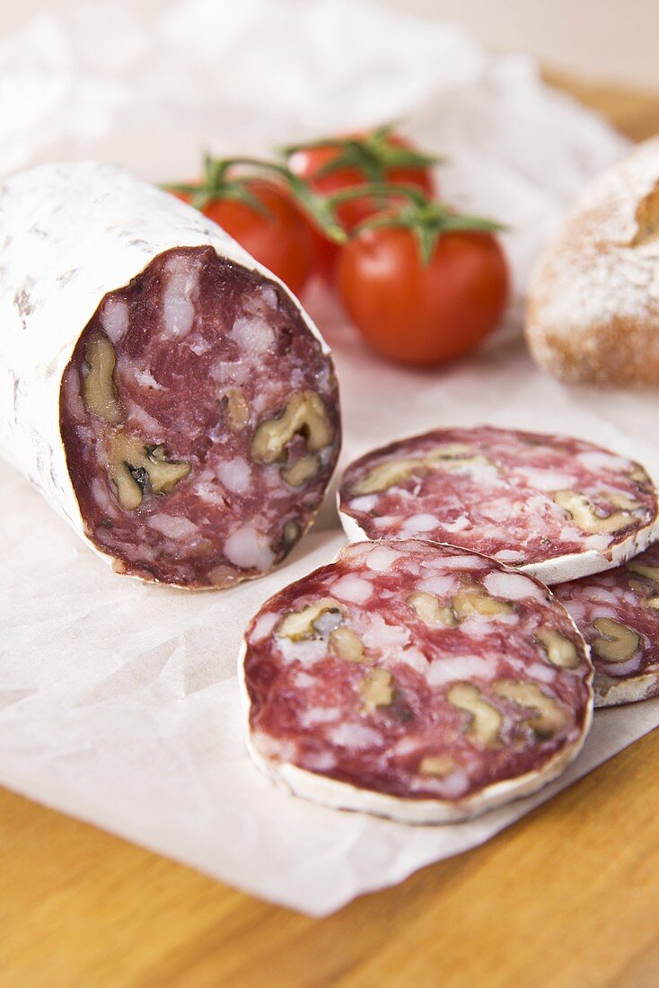 Walnut salami on paper with tomatoes and bread