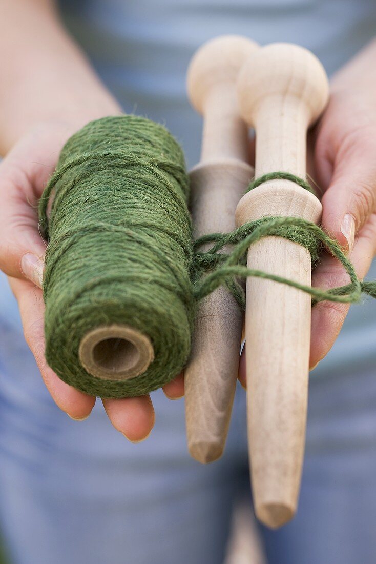 A woman holding twine and wooden pegs