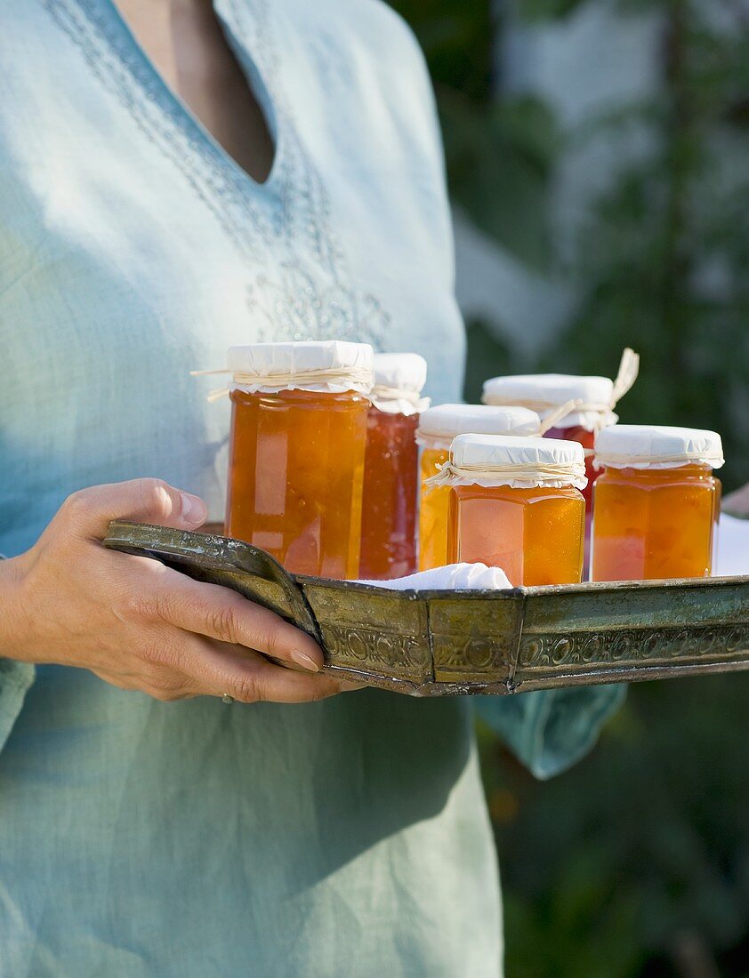 Frau hält Tablett mit Marmeladen