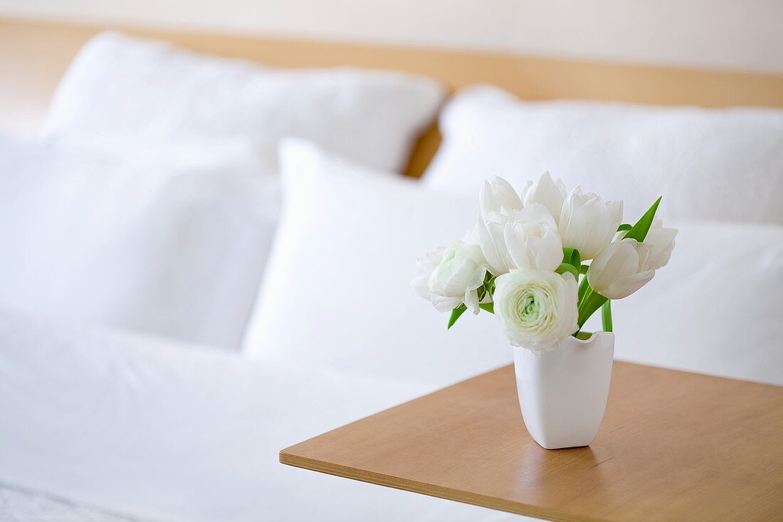 A bouquet of white tulip on a side table in a hotel room