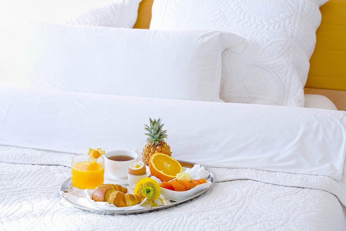 A breakfast tray on a bed in a hotel room