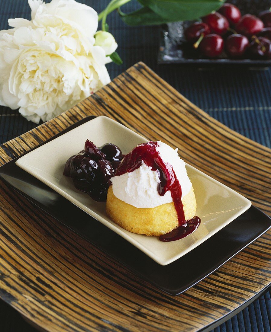 Small sponge cake with icing and cherry compote