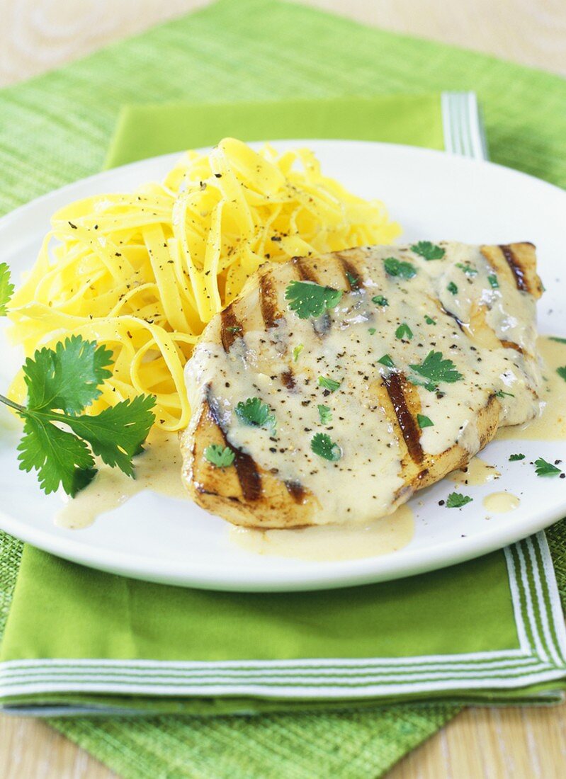 Grilled chicken breast with white sauce and ribbon pasta