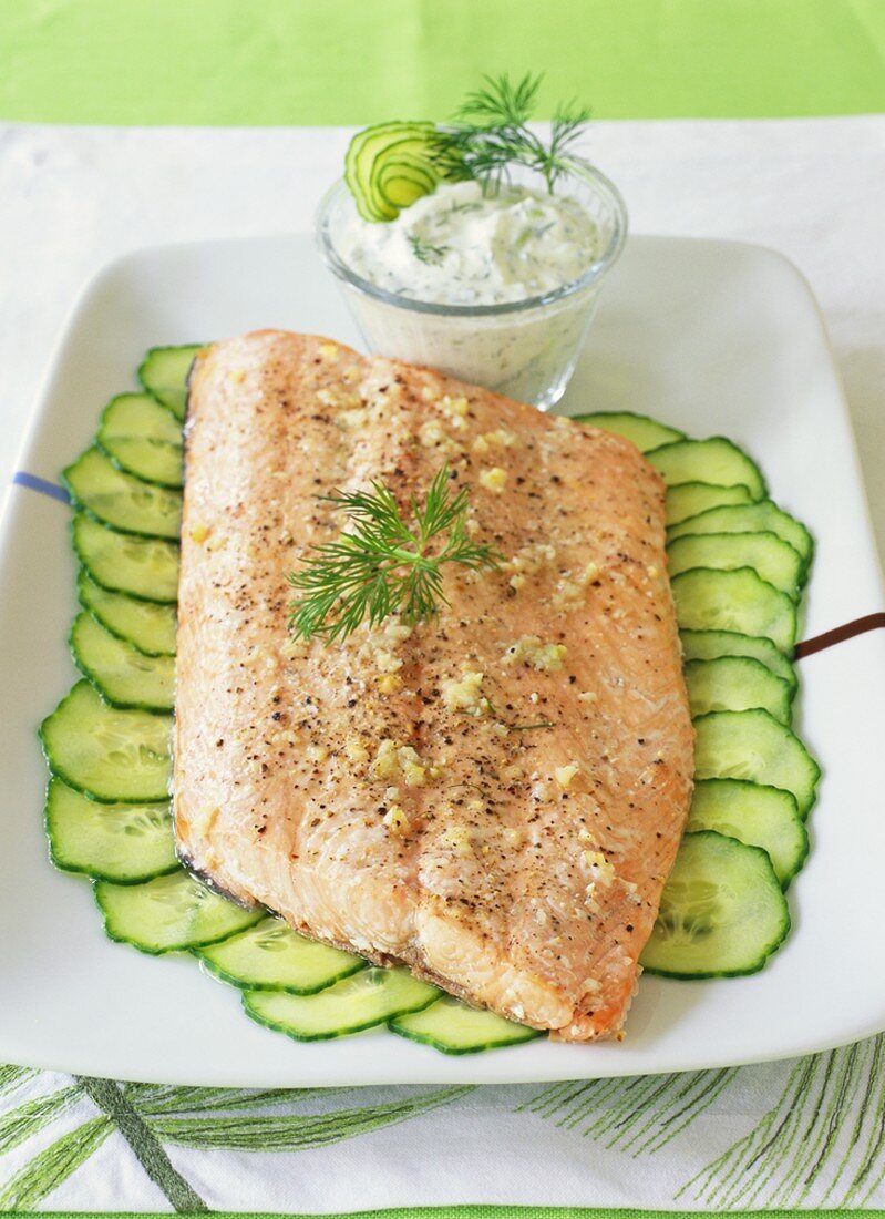 Fried salmon on cucumber slices with dill sauce