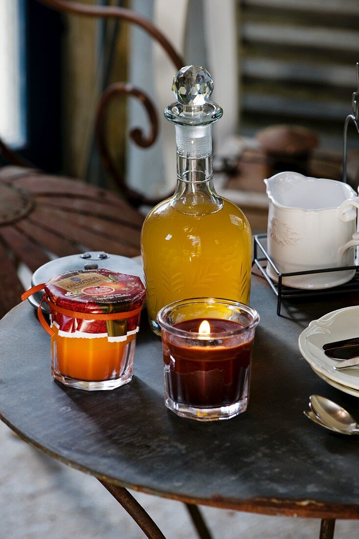 Jam, fruit juice, candle and crockery on metal table