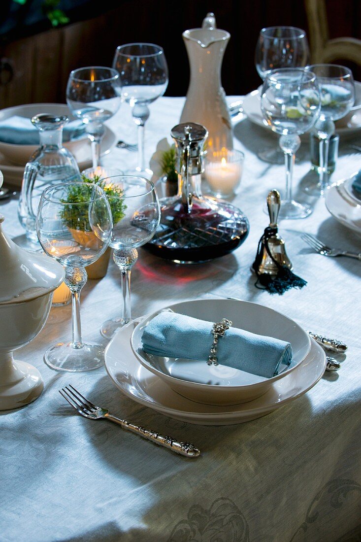 Festlich gedeckter Tisch mit Weinkaraffe, Tischglocke und Kerzen