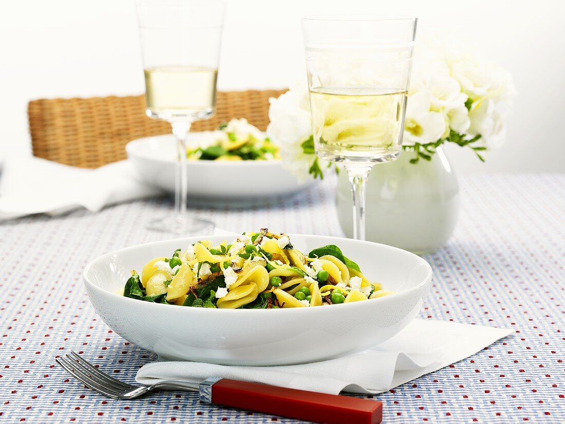 Pasta with peas, cheese & leafy vegetables, glasses of white wine