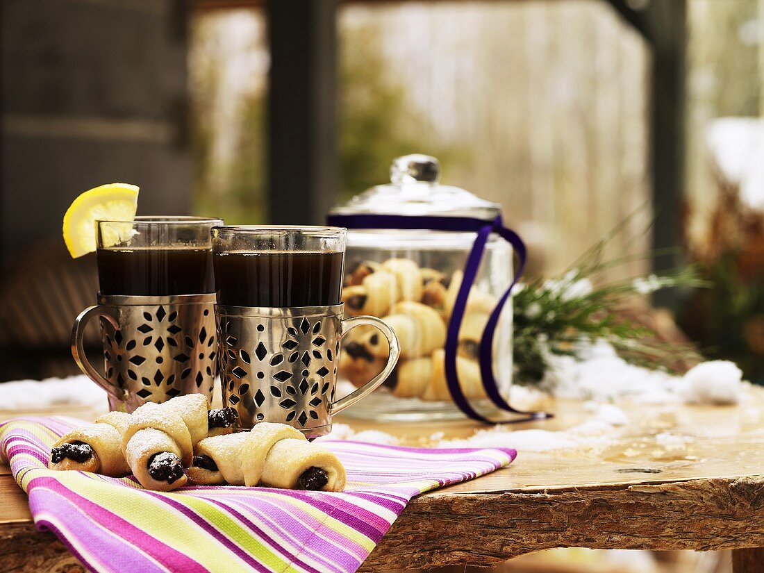 Kaffeegetränke und süsse Hörnchen auf verschneitem Tisch