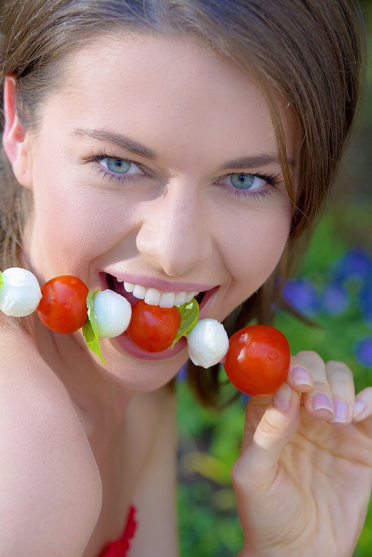 Young woman with tomato and mozzarella skewer
