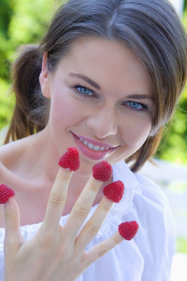 Young woman with raspberries on her fingers