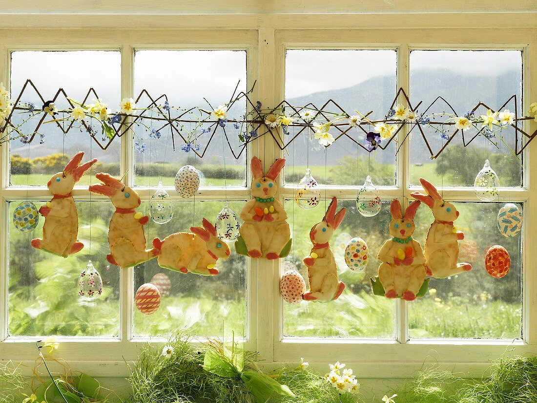 Osterhasen mit Zuckerglasur hängen vor Fenster zur Deko
