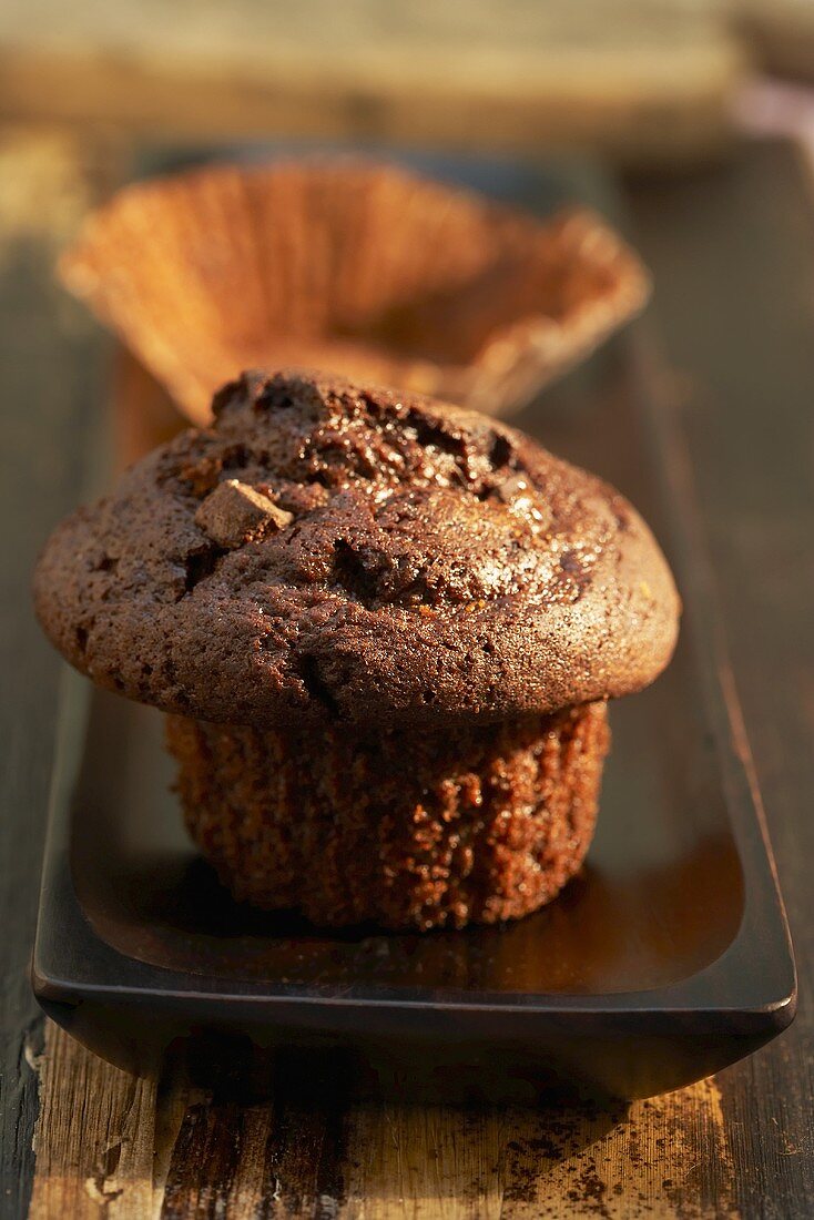 Schokoladenmuffin und leeres Papierförmchen