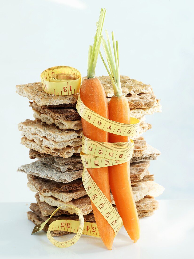 A stack of crispbread and carrots with tape measure