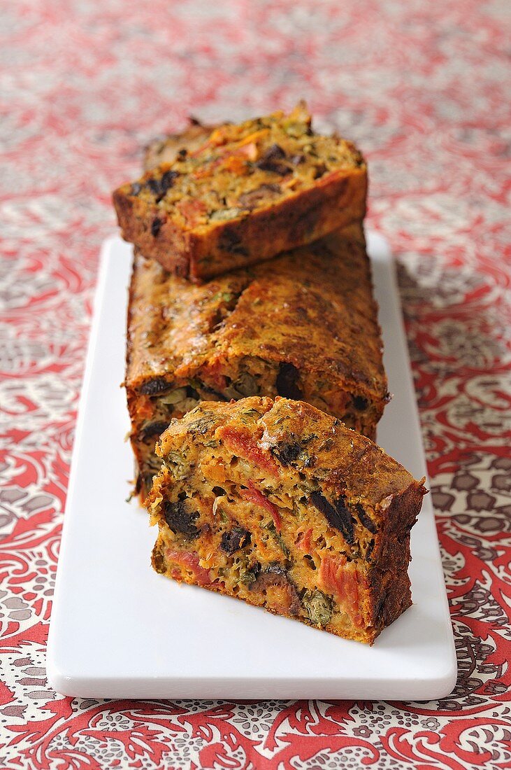 Gemüsekuchen mit Oliven, Tomaten und Sardellen, angeschnitten