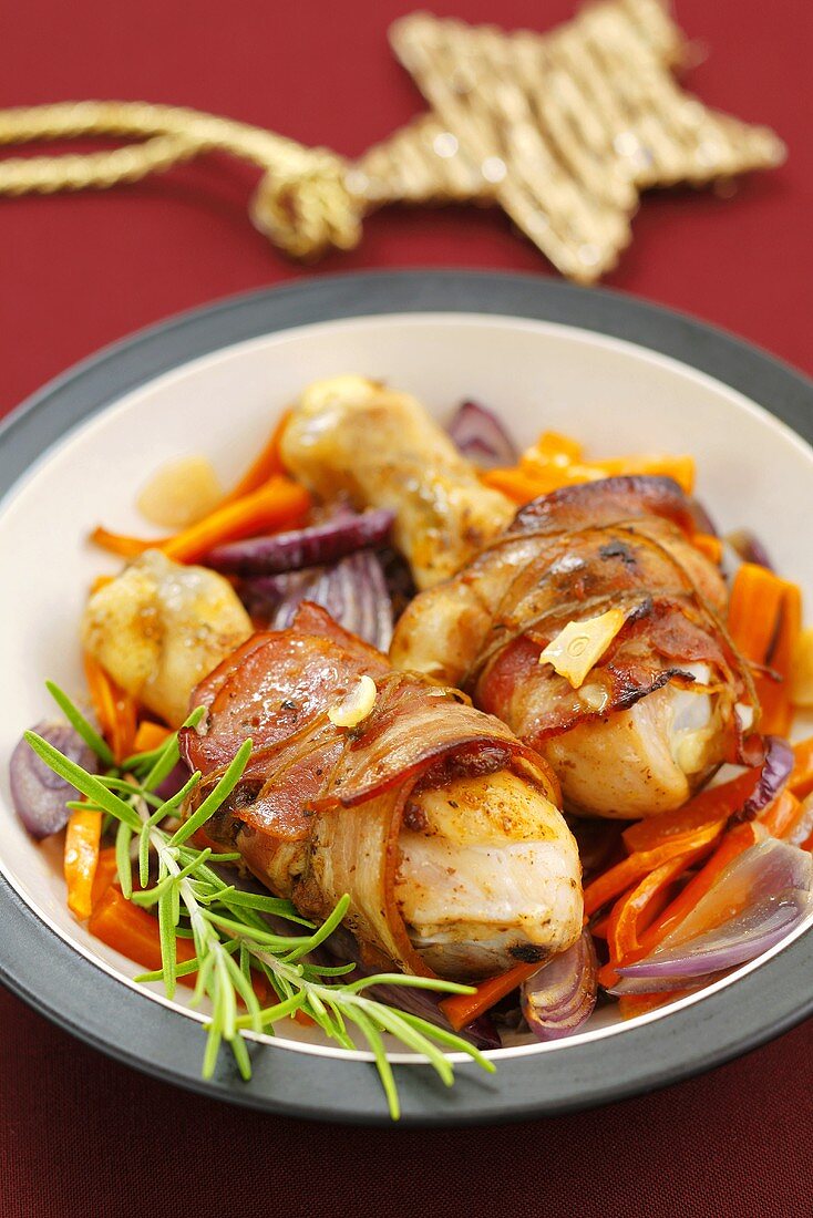 Bacon-wrapped chicken drumsticks on vegetables