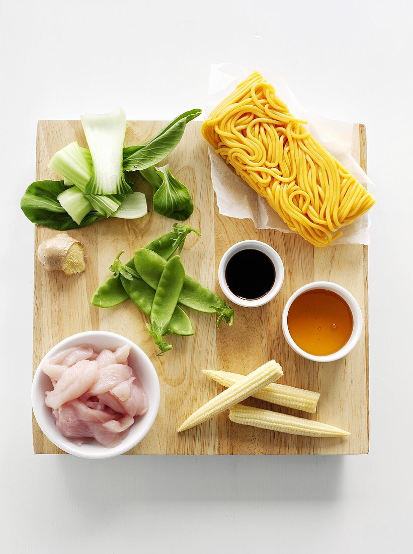Ingredients for Hokkien noodles with chicken on chopping board (overhead)