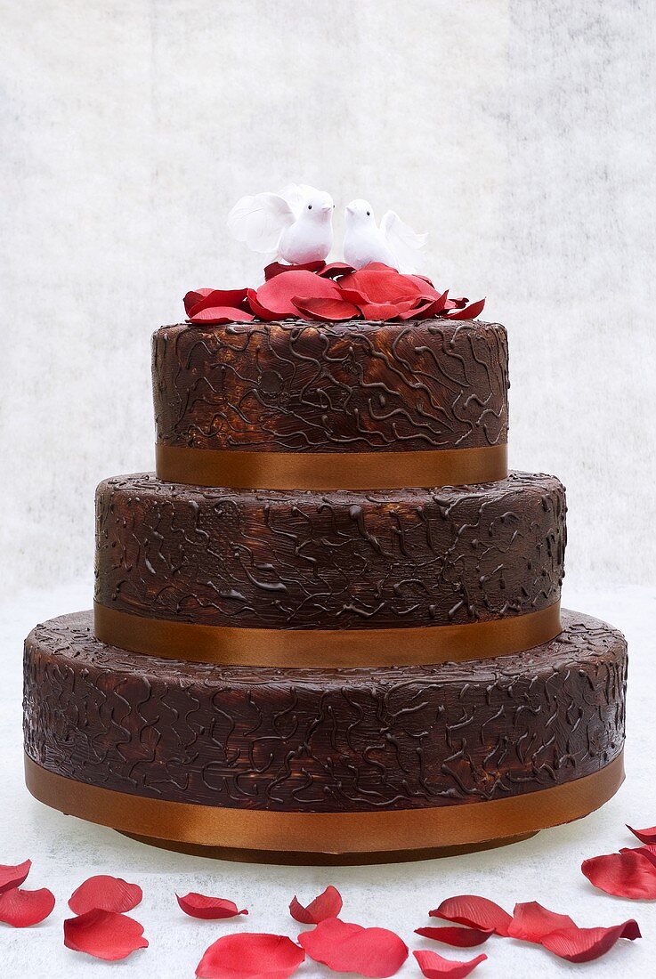 Chocolate wedding cake with rose petals and pair of doves