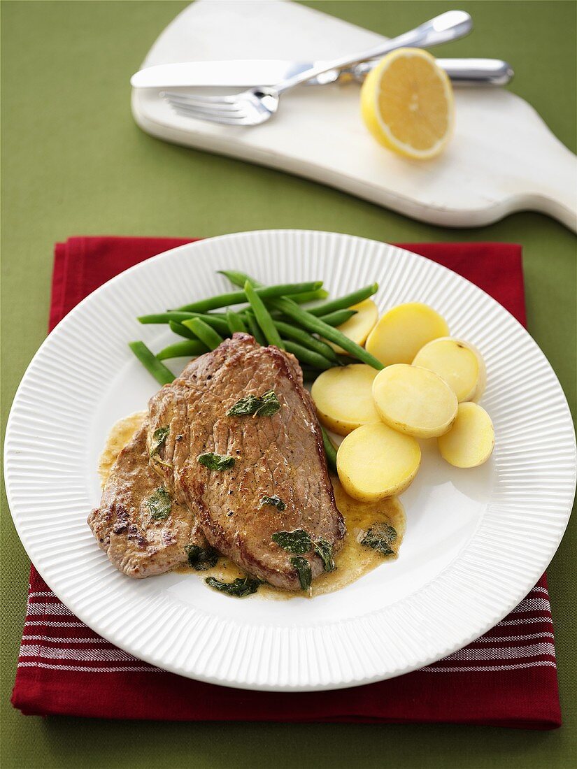 Veal steak with sage and lemon sauce, potatoes and beans
