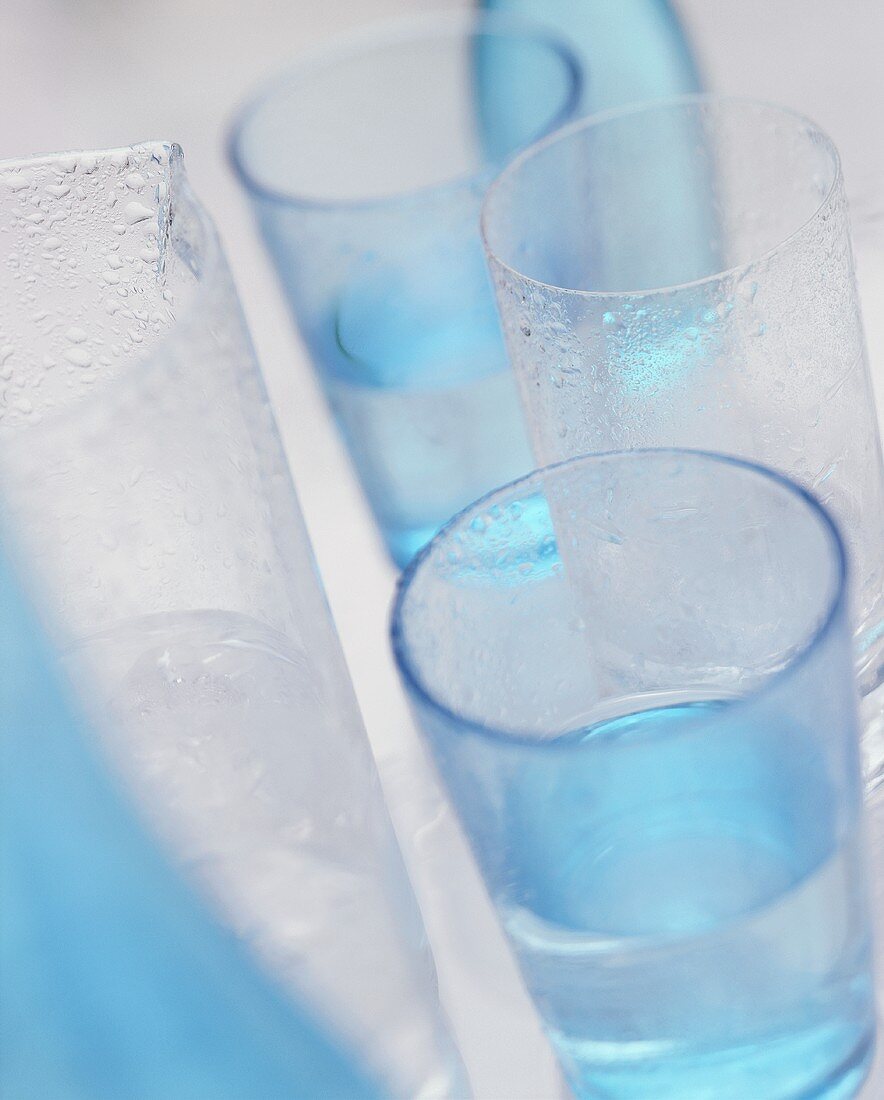 Glasses of water with blue water bottles