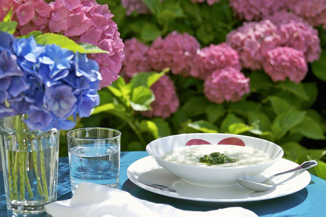 Tisch mit Gemüsecremesuppe und Hortensien im Freien